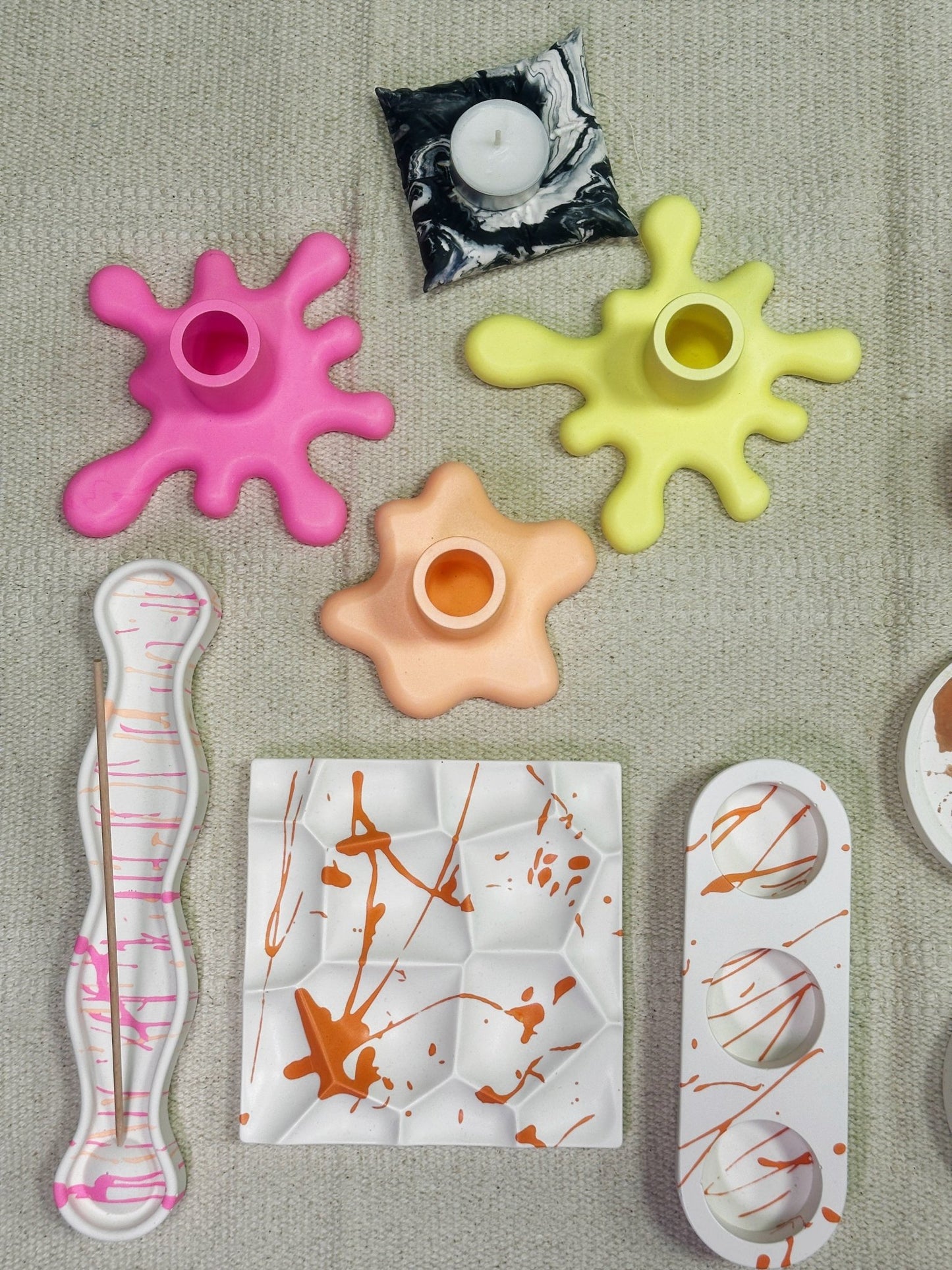 bunte Jesmonite Formen in unterschiedlicher Form auf beigen Untergrund.